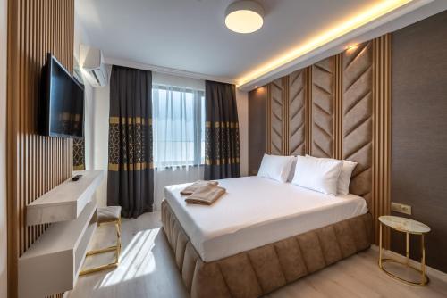 a hotel room with a bed and a television at Santa Maria Luxury Suits in Ravda