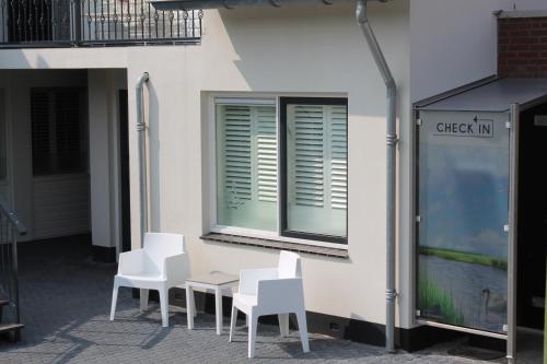 a group of white chairs and a table in front of a building at Hotel Giethoorn in Giethoorn