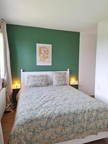 a bedroom with a large bed with a green wall at L'Aubier in Saint-Maur