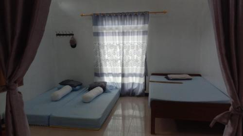 two beds in a room with a window at Naufal homestay & kost in Ngemplak