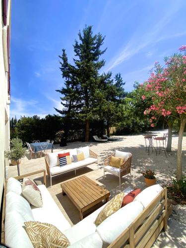 une terrasse avec des canapés, une table et des chaises dans l'établissement Maison avec grand Jardin et Piscine - Capacité 8 Personnes, à Carpentras