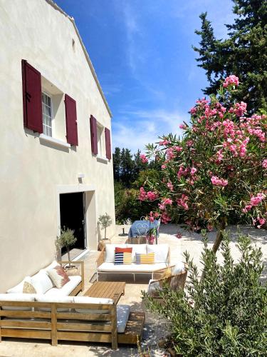 un patio avec deux canapés et un arbre à fleurs roses dans l'établissement Maison avec grand Jardin et Piscine - Capacité 8 Personnes, à Carpentras