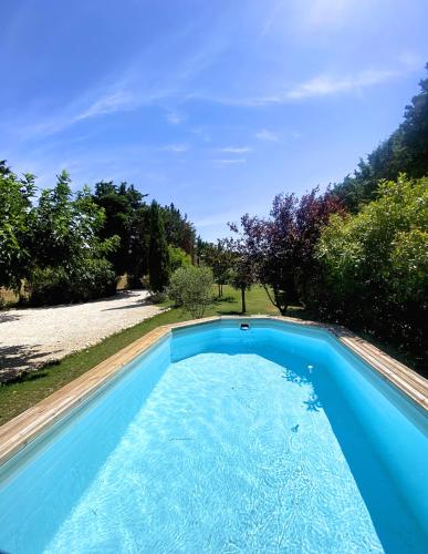 une piscine bleue dans une cour arborée dans l'établissement Maison avec grand Jardin et Piscine - Capacité 8 Personnes, à Carpentras