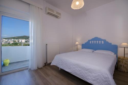 Dormitorio blanco con cama azul y ventana grande en Kallimento, en Kissamos