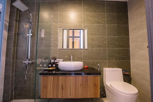 Un baño con lavabo, inodoro y espejo. en Ana La Vie Hue, en Thôn Lại Thê