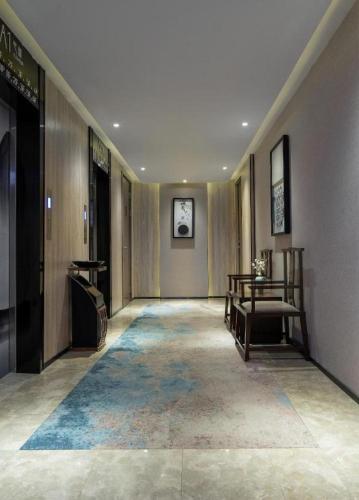 a hallway of a building with a chair and a table at Yuan Culture Hotel Shenzhen World Shajing in Shenzhen