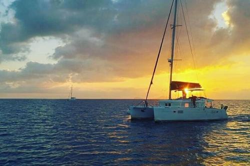 a boat in the ocean with a sunset in the background at Navita Cave Houses in Fira