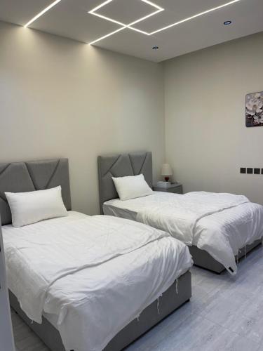 two beds in a room with white walls at شقق في الحمرا هاي رايز in Al Khobar