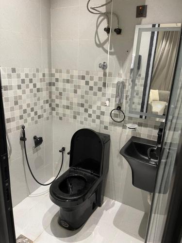 a bathroom with a black toilet and a sink at شقق في الحمرا هاي رايز in Al Khobar