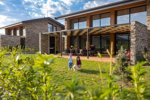 two children walking a dog in front of a building at Hypnotic Thermal Villas in Banya
