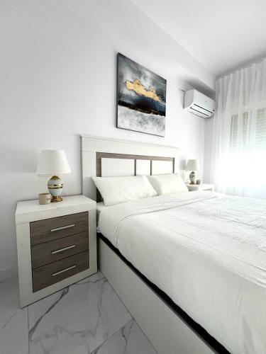 ein weißes Schlafzimmer mit einem großen Bett und einem Nachttisch in der Unterkunft Aguadulce bay apartments 1 in Aguadulce