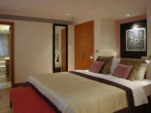 a bedroom with a large bed with pink pillows at Taj Wellington Mews, Mumbai in Mumbai