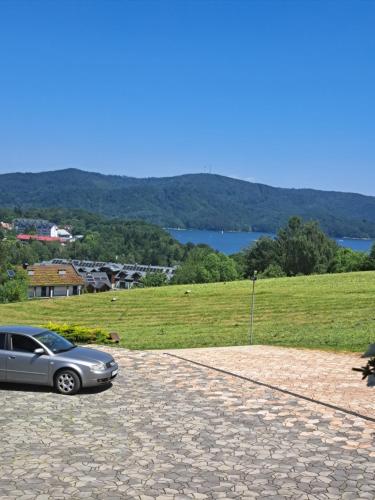 a car parked in a driveway next to a field at Willa Diana- z panoramą jeziora i gór w Polańczyku in Polańczyk