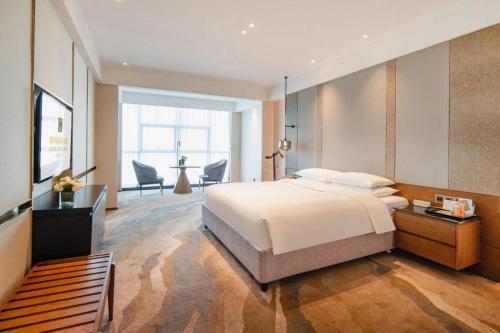 a bedroom with a large bed and a living room at Grand Metropark Hotel Chongqing in Chongqing
