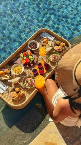 a woman laying on a tray of food next to a pool at Anathera Resort Kuta in Kuta
