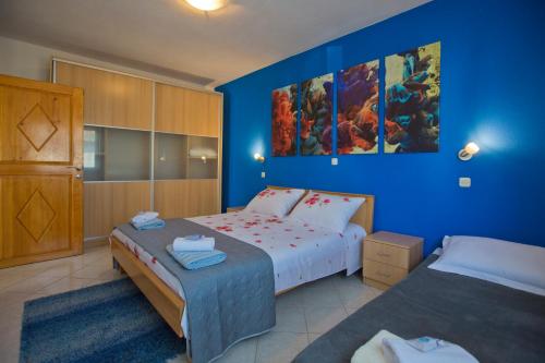 - une chambre avec 2 lits et un mur bleu dans l'établissement Apartment Zdravka, à Hvar