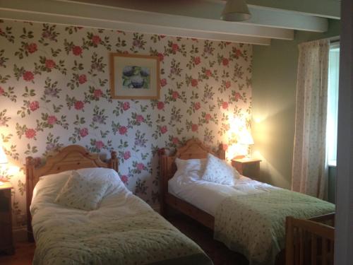 two beds in a room with flowers on the wall at Barcloy Milk House in Kirkcudbright
