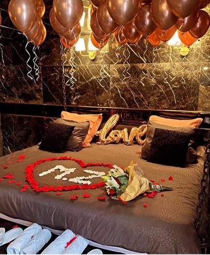 un lit avec un cœur et des ballons dessus dans l'établissement Love room - versace, à Montpellier