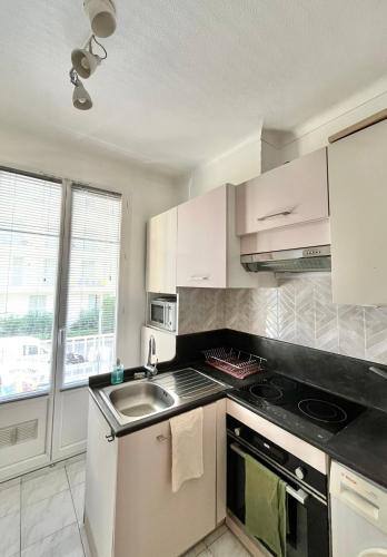 une cuisine avec des armoires blanches et un évier dans l'établissement Cosy apartment - 15 min from beach - Free Parking, à Nice
