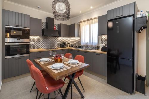 a kitchen with a wooden table with chairs and a black refrigerator at Mater Terra-Private Villa in Sami