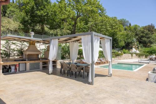 a pavilion with a table and a kitchen and a swimming pool at Mater Terra-Private Villa in Sami