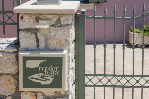 a sign on a stone pillar next to a fence at Mater Terra-Private Villa in Sami