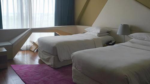 a hotel room with two beds and a window at Vivanta New Delhi, Dwarka in New Delhi