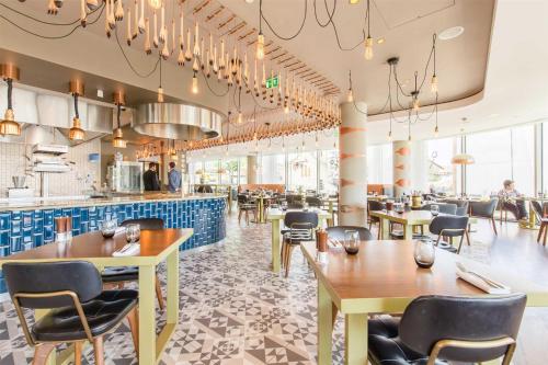 a restaurant with tables and chairs and a bar at Hilton Bournemouth in Bournemouth