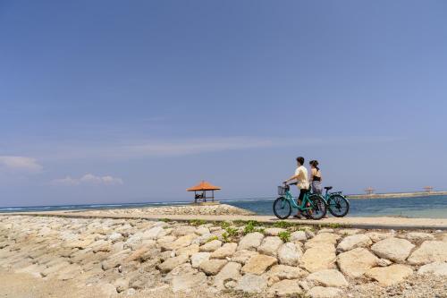 a man and a woman riding bikes on a beach at Griya Santrian a Beach Resort And Spa in Sanur