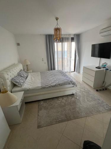 a white bedroom with a bed and a tv at View 1 in Dobra Voda