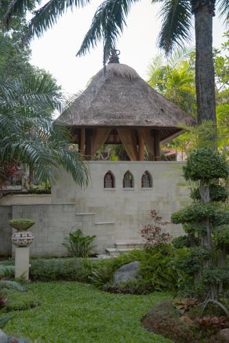 a small building with a thatched roof in a garden at Griya Santrian a Beach Resort And Spa in Sanur