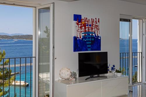 a living room with a television and a balcony at Blue Bay Residence in Hvar