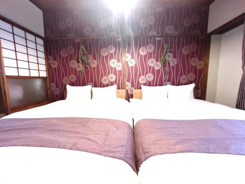 two beds in a room with flowers on the wall at Akabane Nishi kodate AN1 in Wada