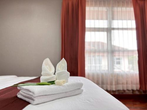 a room with a bed with towels and a window at The Harmony House in Hat Yai in Ban Thung Ri