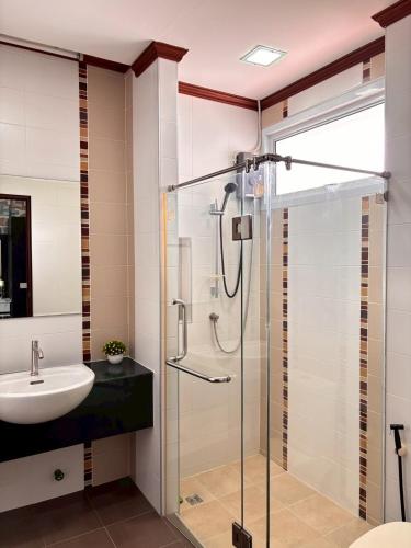 a bathroom with a glass shower and a sink at The Harmony House in Hat Yai in Ban Thung Ri