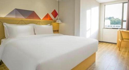a large white bed in a room with a window at Borrman Hotel Zhuhai Gongbei Port Fuhuali Light Rail in Zhuhai