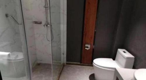 a bathroom with a toilet and a glass shower at Magnotel Shenyang Consulate Qingnian Street in Shenyang