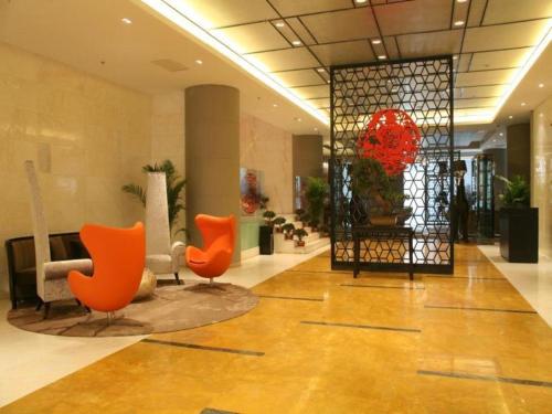 a lobby with orange chairs in a building at Ramada by Wyndham Xi'an Bell Tower in Xi'an