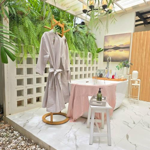 a bathroom with a robe and a bath tub at Mango Villa แมงโก้ วิลล่า in Sa Kaeo