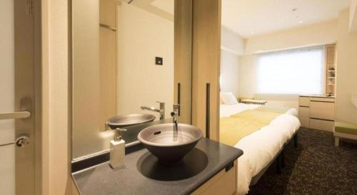 a bathroom with a bowl sink on a counter next to a bed at Hotel Yaenomidori Tokyo in Tokyo