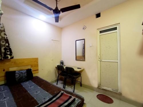 a bedroom with a bed and a desk and a door at VRP Guest House in Bhuj