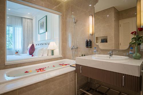 a bathroom with a tub and a sink and a mirror at Legend Valley Hotel Ha Nam in Phủ Lý