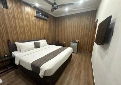 a bedroom with a large bed and a television at Lawrence View Hotel, Lahore in Lahore