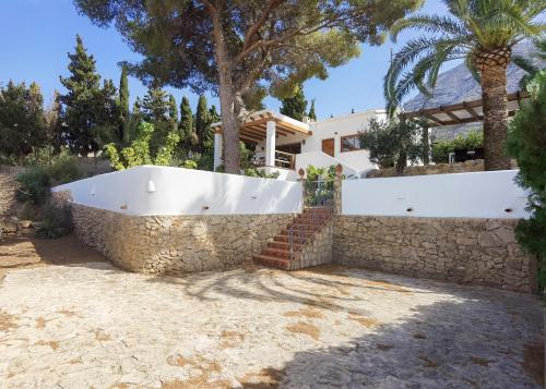 a villa with a swimming pool and a stone wall at Casa Agave in Denia