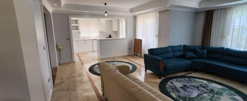 a living room with a blue couch and a kitchen at Ambiance Delux Villa with a Private Pool and a View in Alanya