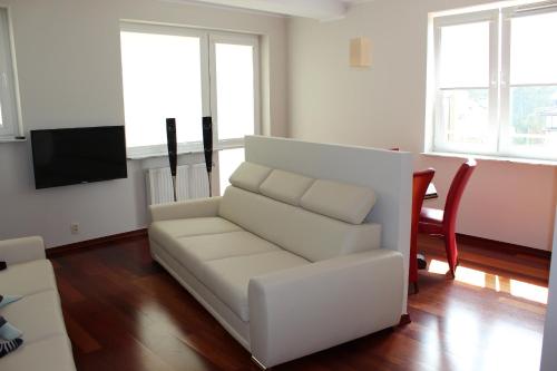 Ustka Apartament Na Wydmie في أوستكا: غرفة معيشة مع أريكة بيضاء وطاولة
