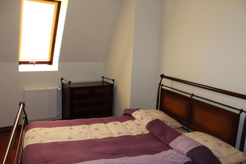 Ustka Apartament Na Wydmie في أوستكا: غرفة نوم بسرير مع اطار خشبي ونافذة