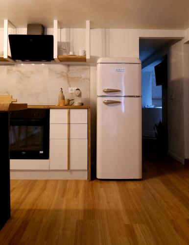 a white refrigerator in a kitchen with a wooden floor at Agada Suite in Aci Castello