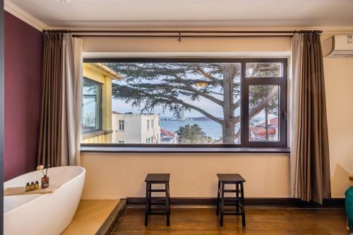 a bathroom with a large window and a tub and stools at September Republic of China Residence in Qingdao in Qingdao