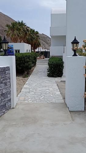a stone walkway next to a white building with a street light at Perissa Black Rock Lotus in Perissa